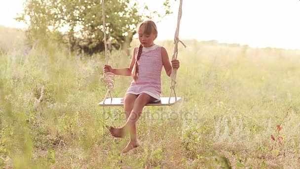 Chica balanceándose en columpio en el parque, columpio en un árbol, unas vacaciones en familia en el parque de verano — Vídeo de stock