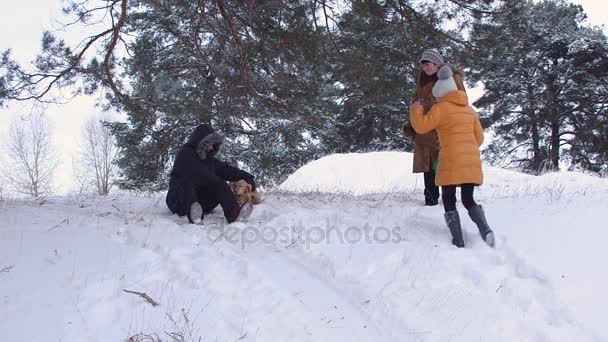Uomo con cane va a fare un giro in slitta in inverno con scivoli di neve, una ragazza e sua nonna ridere, divertente passeggiata in famiglia in inverno snow park, foresta invernale . — Video Stock