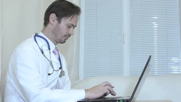 Medico in ufficio che lavora su un computer portatile, uomo in cappotto bianco e cravatta funziona in un ufficio sul computer portatile . — Video Stock