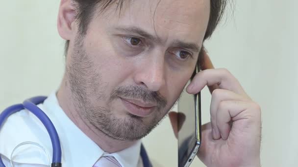 Чоловік лікар розмовляє по телефону в офісі . — стокове відео