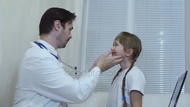 Niños médico mira la garganta del niño en el consultorio, el médico examina a la niña en el consultorio . — Vídeo de stock