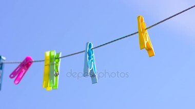 karşı mavi gökyüzü rüzgar sallanan clothesline üzerinde renkli clothespins dönüştürün.