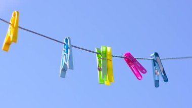 karşı mavi gökyüzü rüzgar sallanan clothesline üzerinde renkli clothespins dönüştürün.