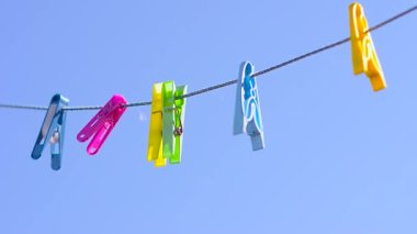 karşı mavi gökyüzü rüzgar sallanan clothesline üzerinde renkli clothespins dönüştürün.