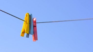 renkli giysiler mandal üzerinde çamaşır ipi, mavi gökyüzü arka plan üzerinde salıncak.
