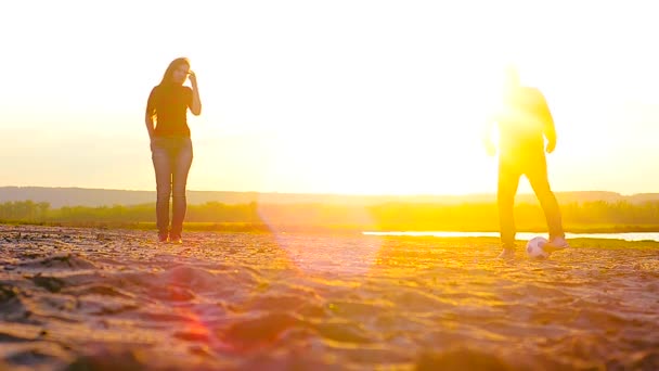 Chica y hombre jugando al fútbol en la playa en el sol . — Vídeos de Stock