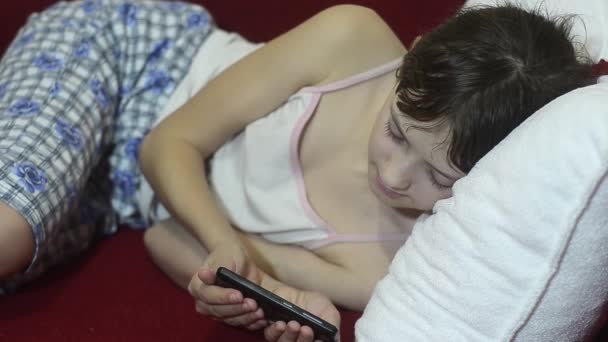 Jeune fille adolescent sur le canapé lecture e-mail dans le téléphone . — Video