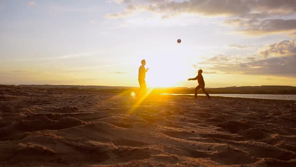 Os homens jogam voleibol na areia ao sol, vôlei de praia na noite de verão . — Vídeo de Stock