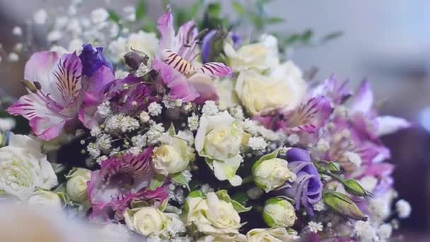 Hermosas flores de colores están en la mesa. ramo de flores blancas, púrpuras y rojas en la mesa . — Vídeos de Stock