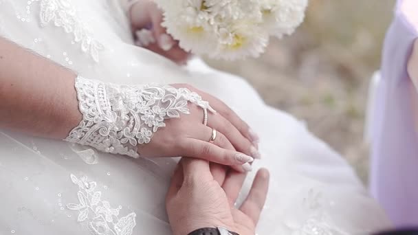 Mano hombre acaricia la mano de una chica en un vestido blanco con un ramo de flores blancas . — Vídeo de stock