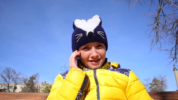 Teen κορίτσι μιλάει στο τηλέφωνο σε πάρκα σε φόντο του ουρανού. — Αρχείο Βίντεο