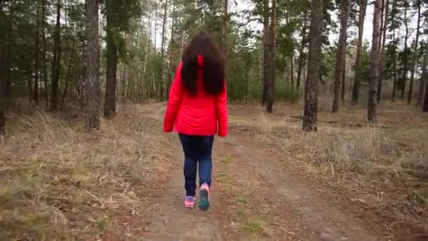 Ung flicka i röd jacka promenader i parken under våren — Stockvideo
