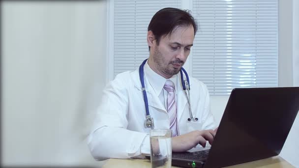 Médico no escritório trabalhando em um laptop . — Vídeo de Stock