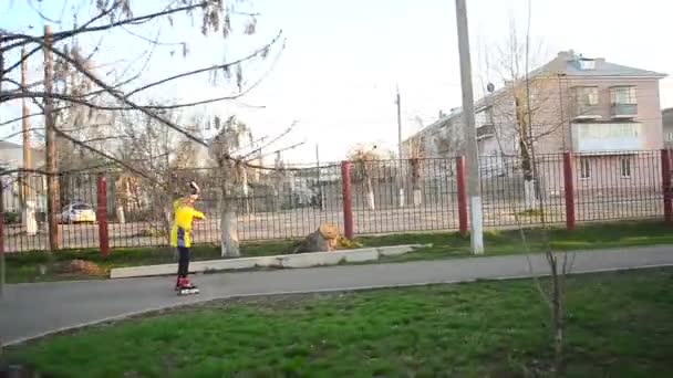 Niña aprende a patinar en el parque de la ciudad — Vídeos de Stock