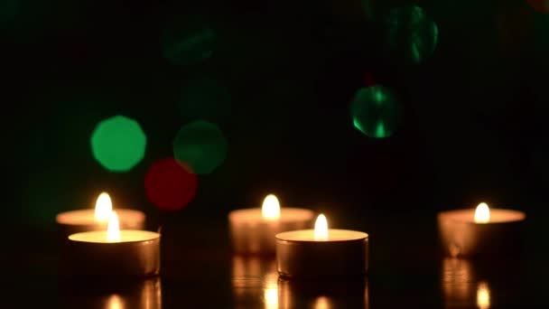 Velas na mesa em escuro, decoração festiva do quarto, contra o pano de fundo de bokeh brilhante colorido . — Vídeo de Stock