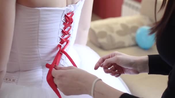 白の美しいドレスの女の子が白いドレスに赤いリボンを結ぶ — ストック動画