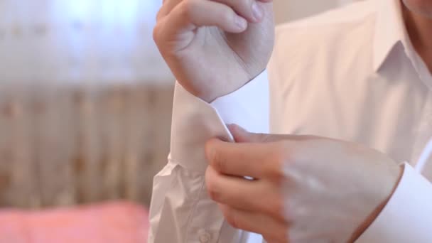 Man fastens buttons on sleeve of the white shirt, man puts on a white shirt. — Stock Video