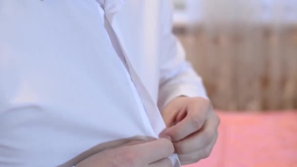 Чоловік одягає білу сорочку, чоловік застібає кнопки на білій сорочці . — стокове відео