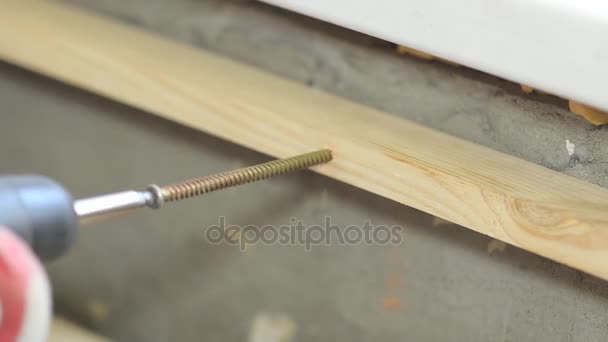 Pracownik skręca śrubę do drewniane deska Wkrętak elektryczny, remonty domu — Wideo stockowe