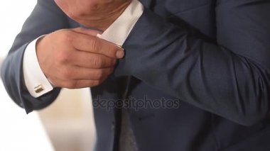 Takım elbiseli adam onun kollu beyaz gömlek ayarlar.