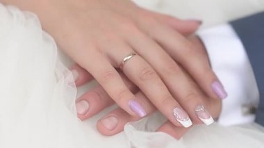 bir buket çiçek kırmızı ve beyaz gül elinde gelinin koyu elbiseli bir adam ile oturan beyaz elbiseli kız ile erkek ve kadın el.