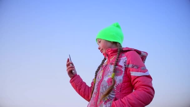 Teen girl photographed telephone, against a blue sky. — Stock Video