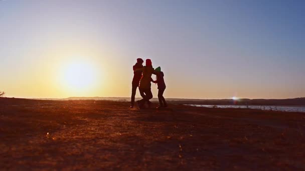 La madre joven se convierte con los niños en una puesta de sol en la noche — Vídeo de stock
