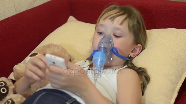 Sick child at childrens hospital plays in phone, girl ingaliruut inhaling steam treatment — Stock Video