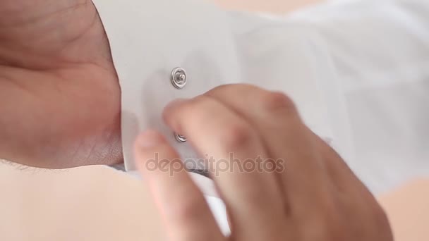 Ο άνθρωπος στερεώνει κουμπιά στο μανίκι του άσπρο πουκάμισο, άνθρωπος βάζει σε ένα λευκό πουκάμισο. — Αρχείο Βίντεο