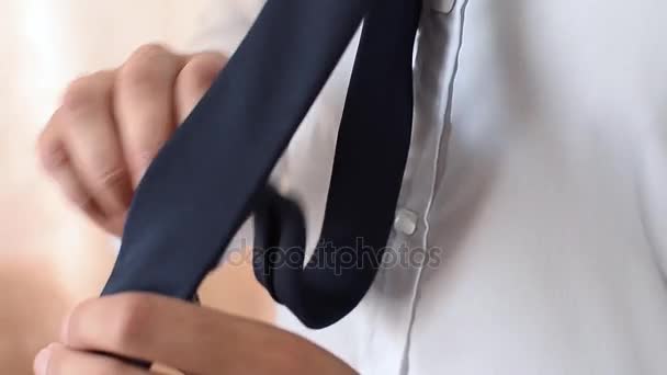 Чоловік зав'язує чорну краватку на білій сорочці, крупним планом — стокове відео
