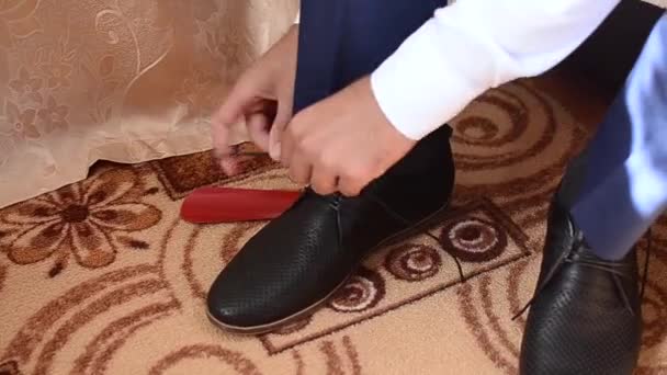 Mann schnürt Schnürsenkel an schwarzen Schuhen, Mann in weißem Hemd und dunkler Hose — Stockvideo