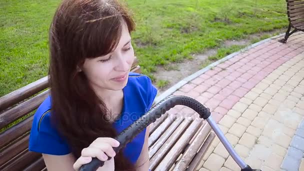 Schöne junge Mutter spaziert mit Kinderwagen im Park. — Stockvideo