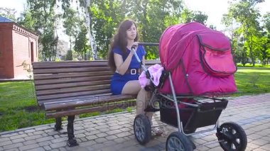 genç anne ile bebek arabası Park yürüme.