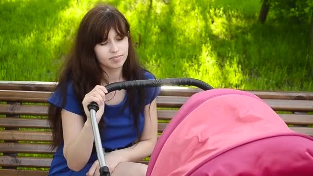 Красива молода мати гуляє з дитячою коляскою в парку . — стокове відео