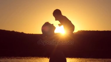 Anne ve bebek günbatımında oynuyorlar. Ağır çekim.