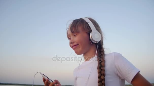 携帯電話とヘッドフォンでは 10 代の少女の踊り. — ストック動画