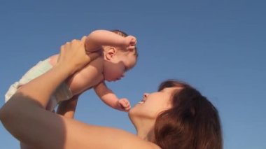 Anne küçük çocuk onun kollarında tutar ve mavi gökyüzü arka planı sarılarak