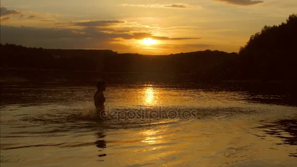 Menina ao pôr do sol jogando na água, as mãos da menina salpicando água, câmera lenta — Vídeo de Stock