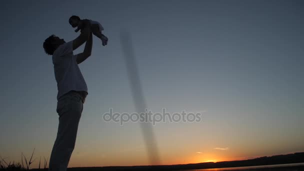 Padre sostiene al pequeño bebé en brazos al atardecer. Movimiento lento . — Vídeo de stock