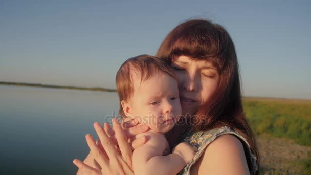 Baby is holding young mother in her arms and smiling. Slow motion. — Stock Video