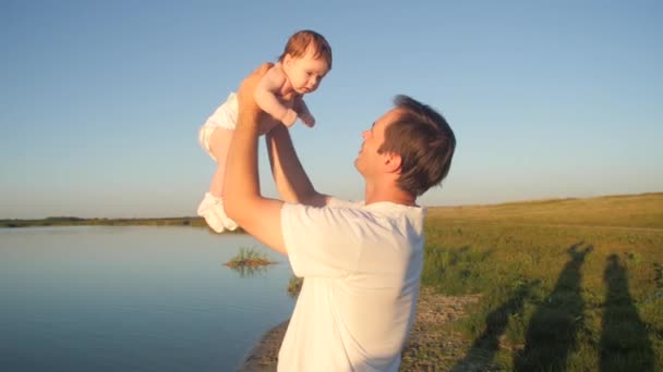 Baby raised in blue sky by his fathers hands, slow motion — Stock Video