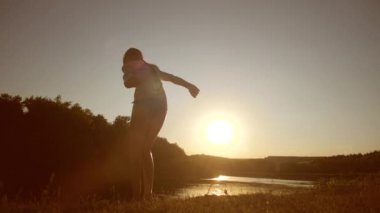 genç kız nehirde cliff, günbatımı, yavaş çekim karşı ile atlamak