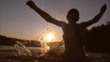 gün batımı suda oynarken, genç kız, kız sıçramasına su eller.