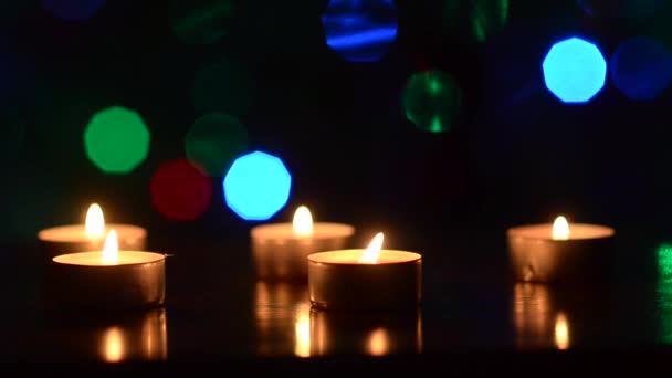 Queimando velas em uma mesa em um quarto escuro, decoração festiva do quarto, piscando colorido bokeh coração azul vermelho verde . — Vídeo de Stock