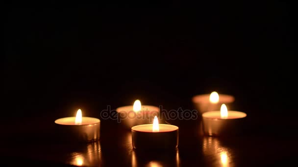 Kerzen auf dem Tisch in der Dunkelheit, festliche Dekoration des Raumes, vor dem Hintergrund des bunten Bokeh, das im Hintergrund leuchtet. — Stockvideo