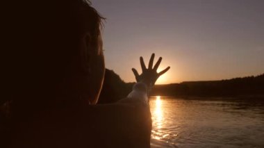 Kız elini güneşin altında Nehri üzerinde günbatımı genişletir