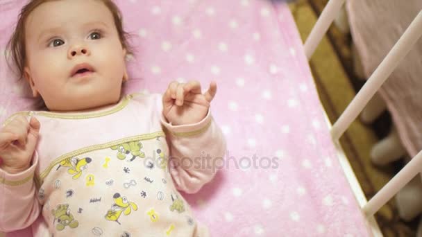 Baby in lichaam ligt op zijn rug in de wieg en kijkt naar het speelgoed. Slow motion, — Stockvideo