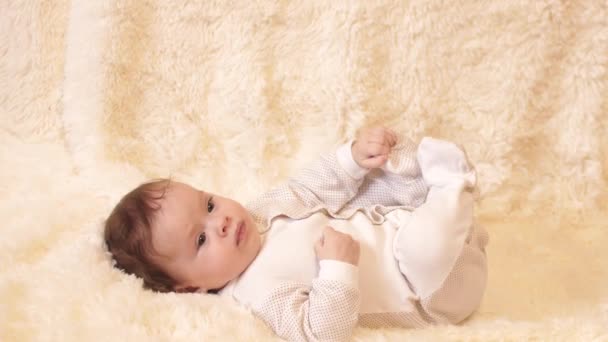 Όμορφο μωρό βρίσκεται στο πίσω στον καναπέ και παίζει — Αρχείο Βίντεο