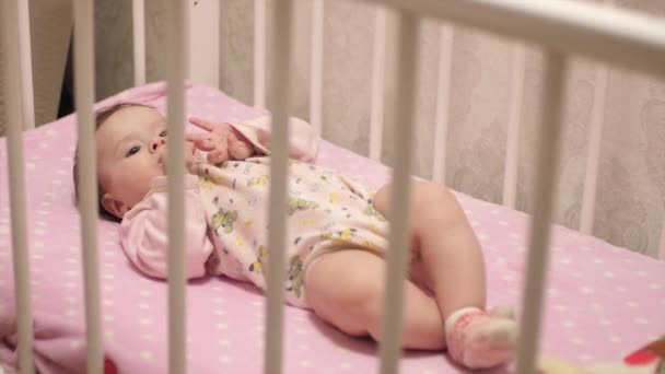 Dziecko leży na powrót w łóżeczkach niemowlęcych. Zwolnionym tempie, — Wideo stockowe