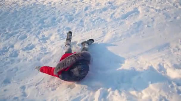 Lyckligt barn glider över snö bild på släde och leenden. liten flicka spelar i vinter i parken — Stockvideo